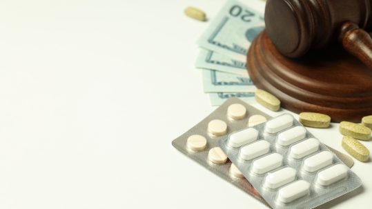Pills with gavel of justice and money, medical corruption concept.